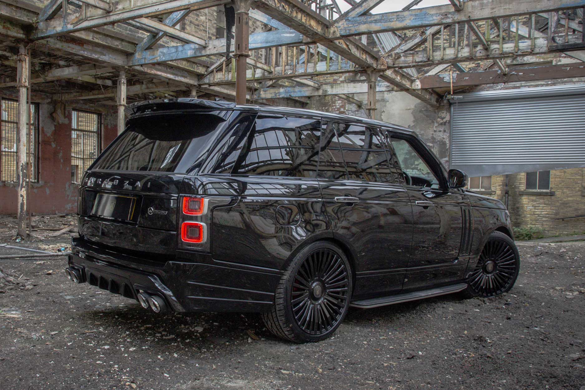 Rear quarter view of a Black Range Rover Vogue L405 2018-2021. Shot outside an urban and gritty abandoned unit. Fitted with Barugzai Casanova 22/23” alloy wheels, in Gloss Black