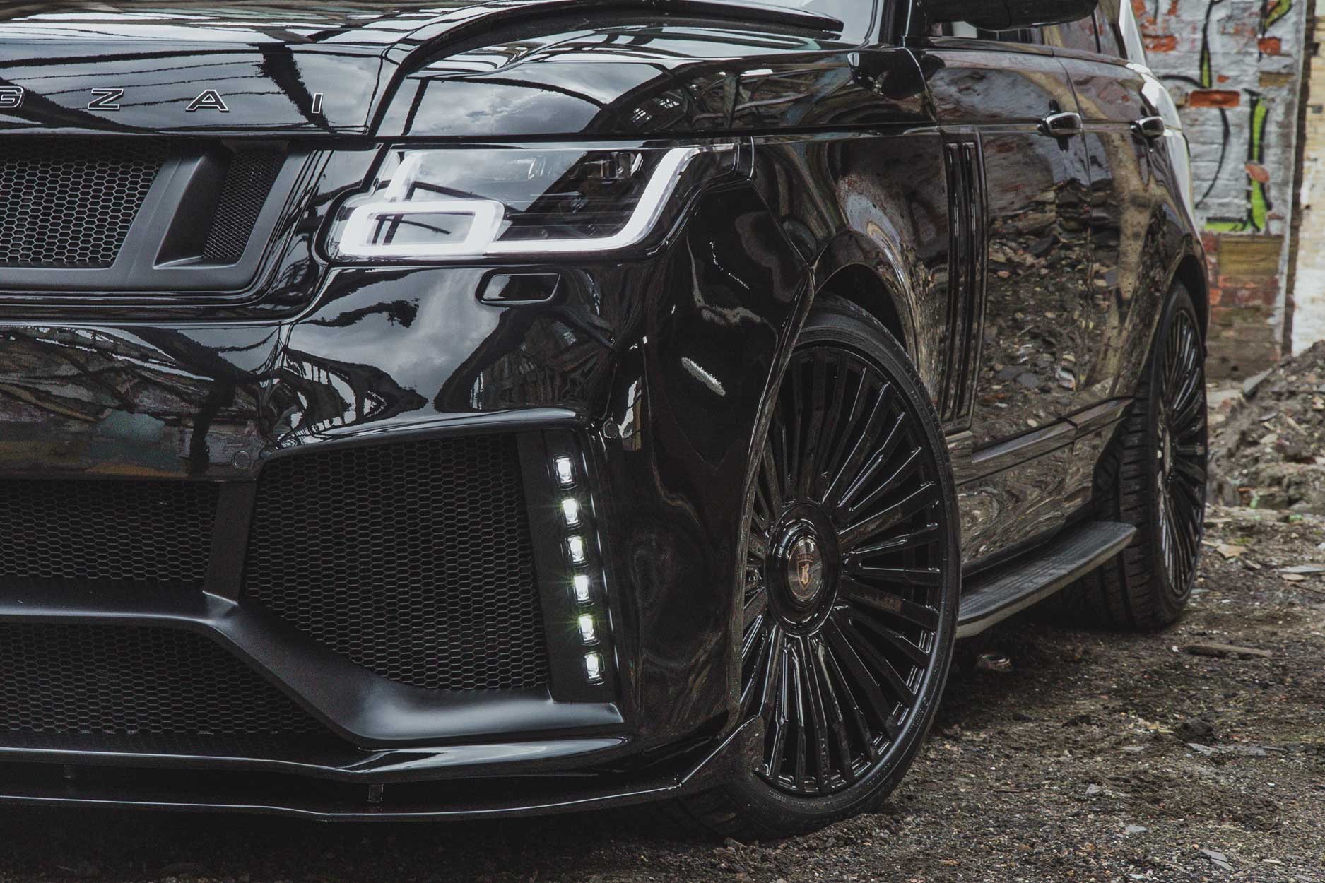 Front quarter detail view of a Black Range Rover Vogue L405 2018-2021. Shot outside an urban and gritty abandoned unit. Fitted with Barugzai Casanova 22/23” alloy wheels, in Gloss Black