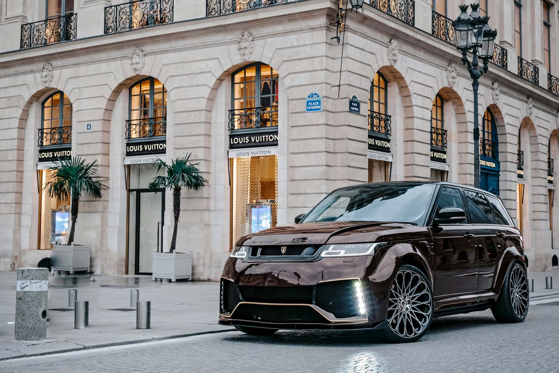 Front quarter view of a Brown Range Rover Sport L494 2018-2022. Shot outside Paris high street. Fitted with Barugzai Majestic 24” alloy wheels, in Gloss Black Polished Face.