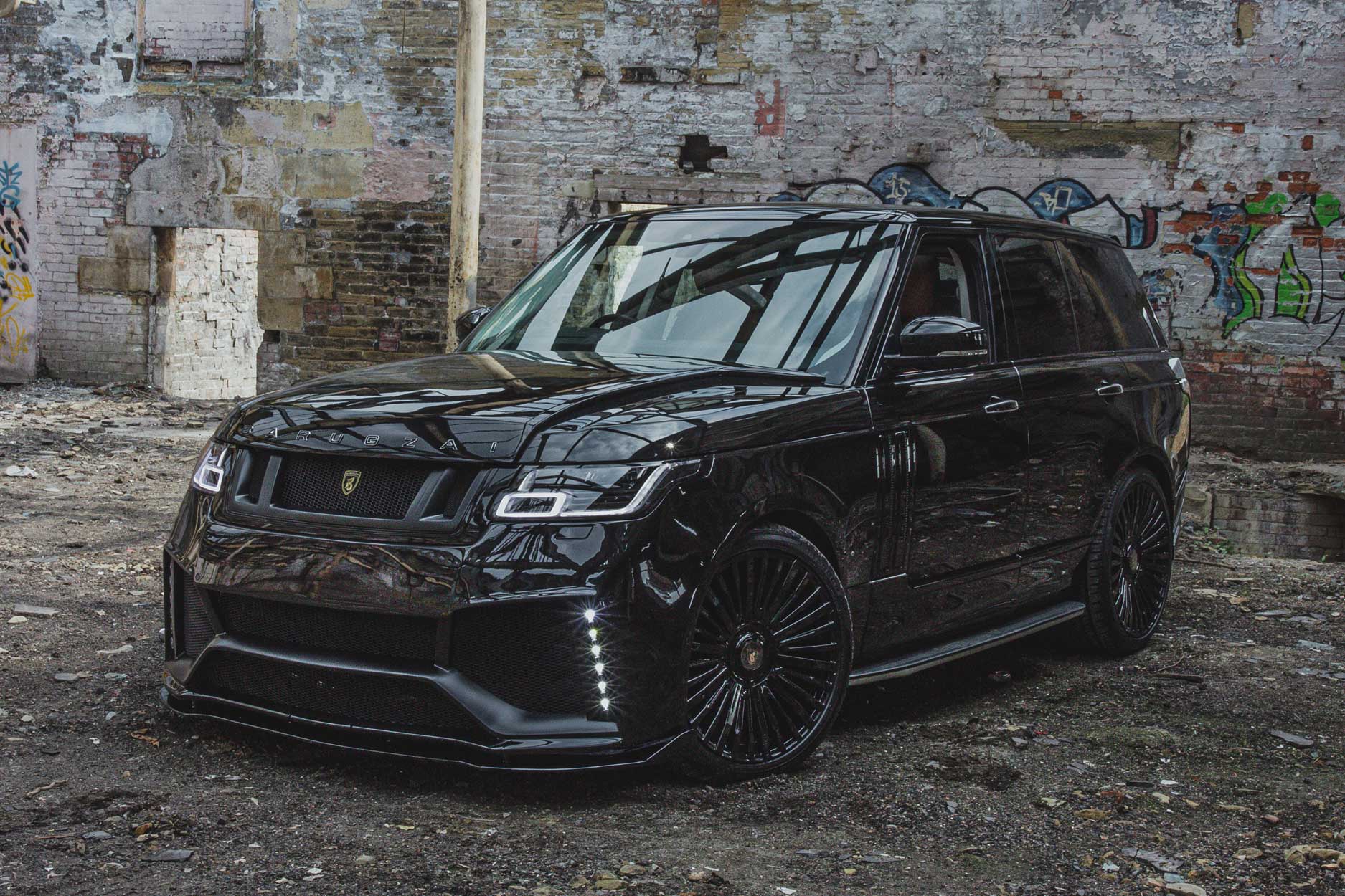 Front quarter view of a Black Range Rover Vogue L405 2018-2021. Shot outside an urban and gritty abandoned unit. Fitted with Barugzai Casanova 22/23” alloy wheels, in Gloss Black