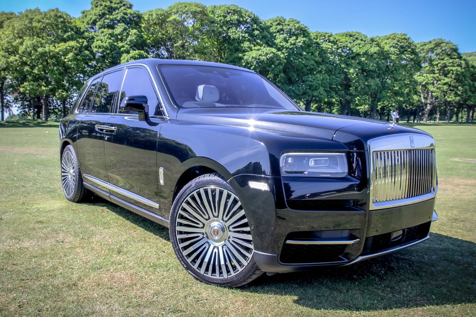 ront quarter view of a Black Rolls Royce Cullinan 2018+. Shot outside a large lawn backdrop. Fitted with Barugzai Casanova 22/23” alloy wheels, in Gloss Black Polished Face.