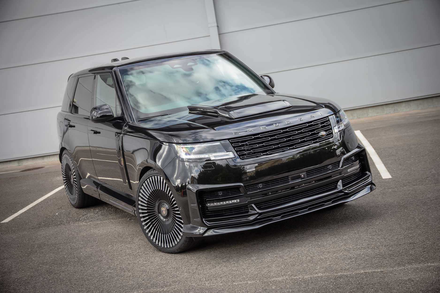 Front quarter view of a Black Range Rover L460 2022+ with a Scoop fitted. Parked on a road with a grey backdrop. Fitted with Barugzai Vortex Forged 24” alloy wheels, in Gloss Black Polished Face.