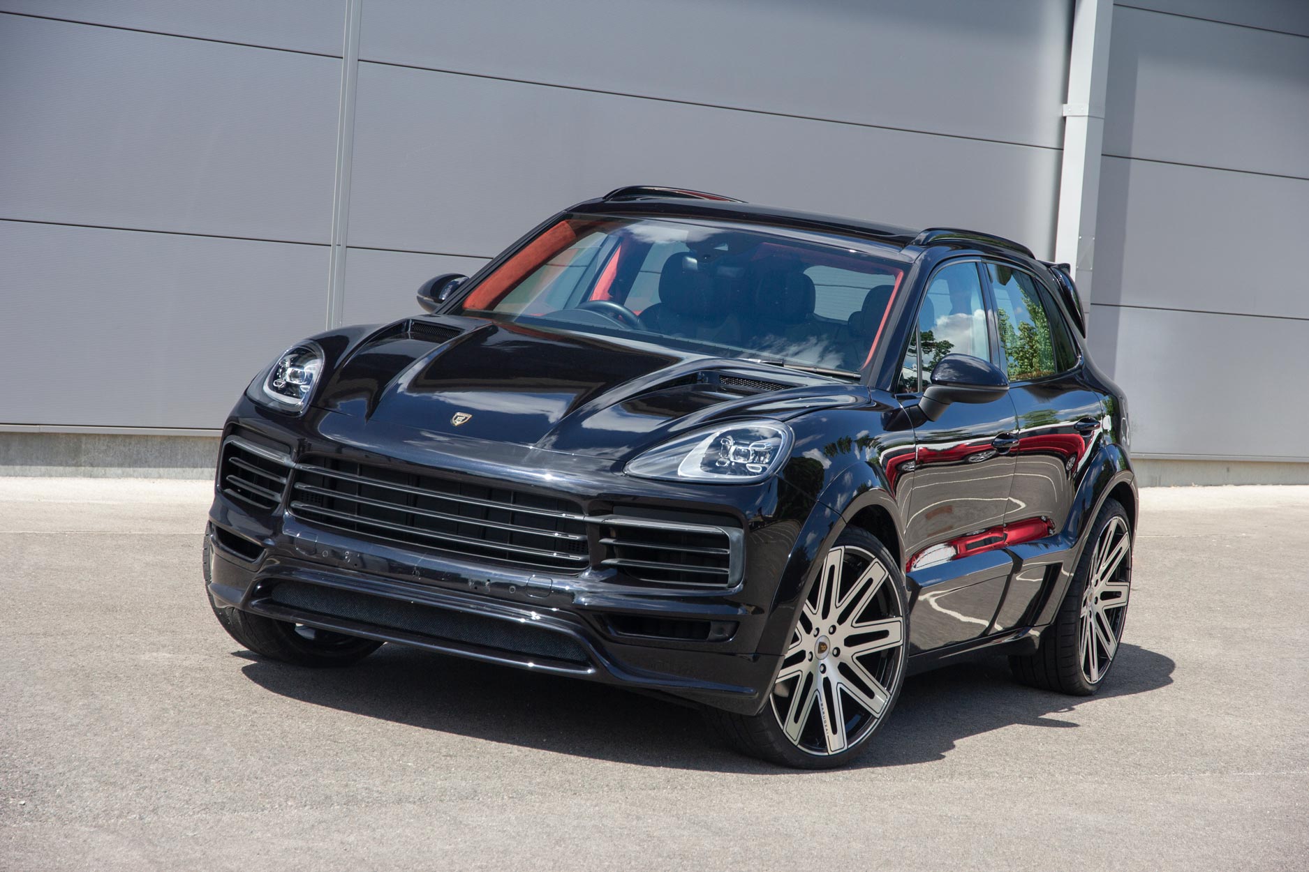 Front quarter view of a Blue Porsche Cayenne 9YA 2019+. Shot outside a carpark with a grey backdrop. Fitted with Barugzai EXEL 24” alloy wheels, in Gloss Black Polished Face.