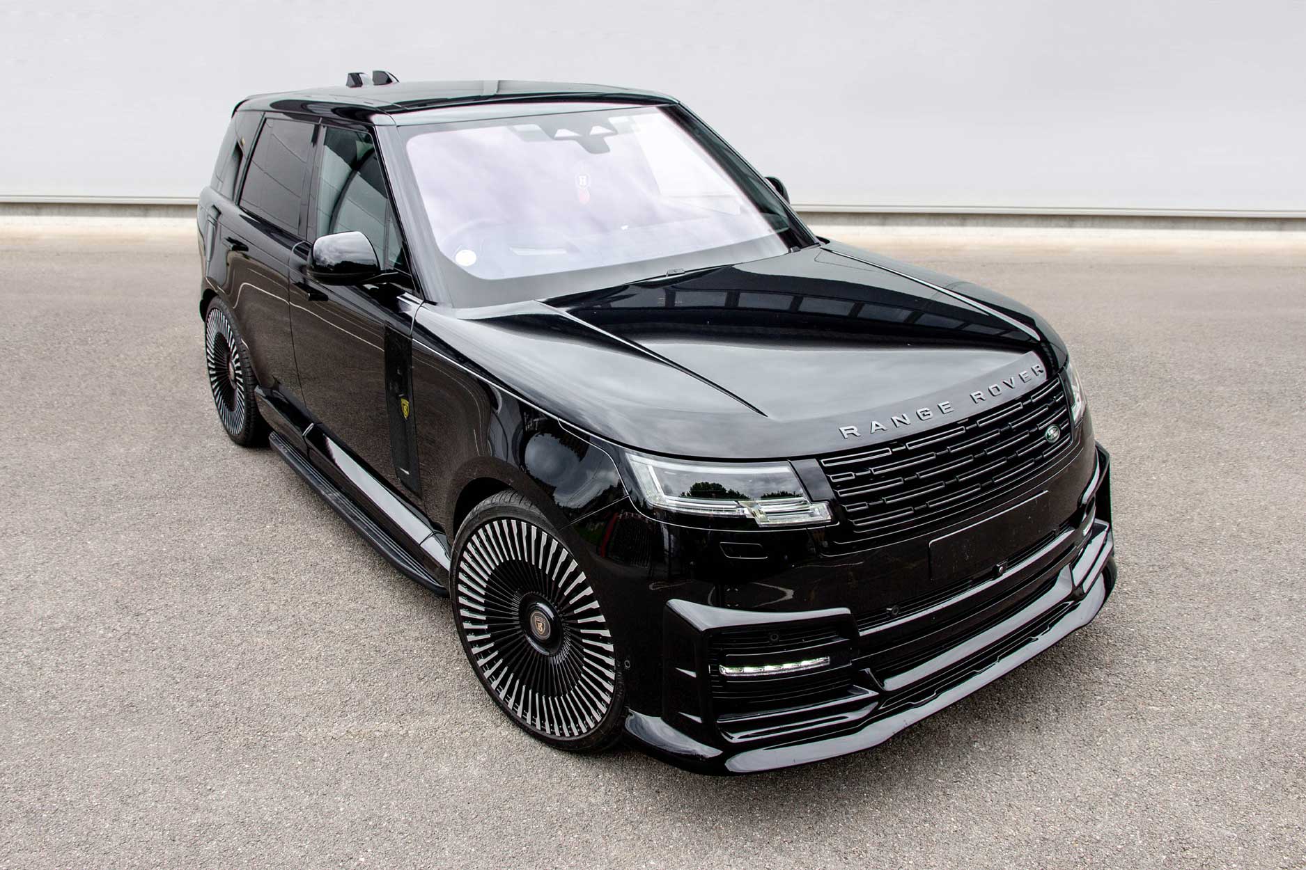 Front quarter view of a Black Range Rover L460 2022+. Parked on a road with a grey backdrop. Fitted with Barugzai Vortex Forged 24” alloy wheels, in Gloss Black Polished Face.