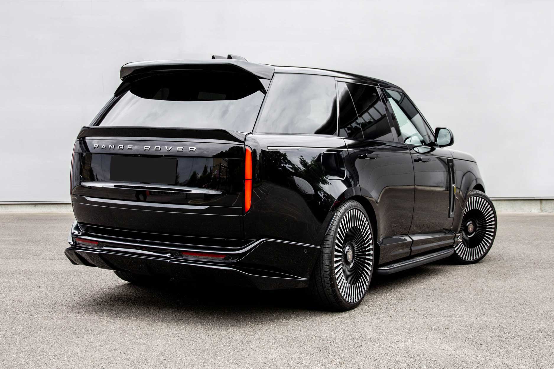 Rear quarter view of a Black Range Rover L460 2022+. Parked on a road with a grey backdrop. Fitted with Barugzai Vortex Forged 24” alloy wheels, in Gloss Black Polished Face.