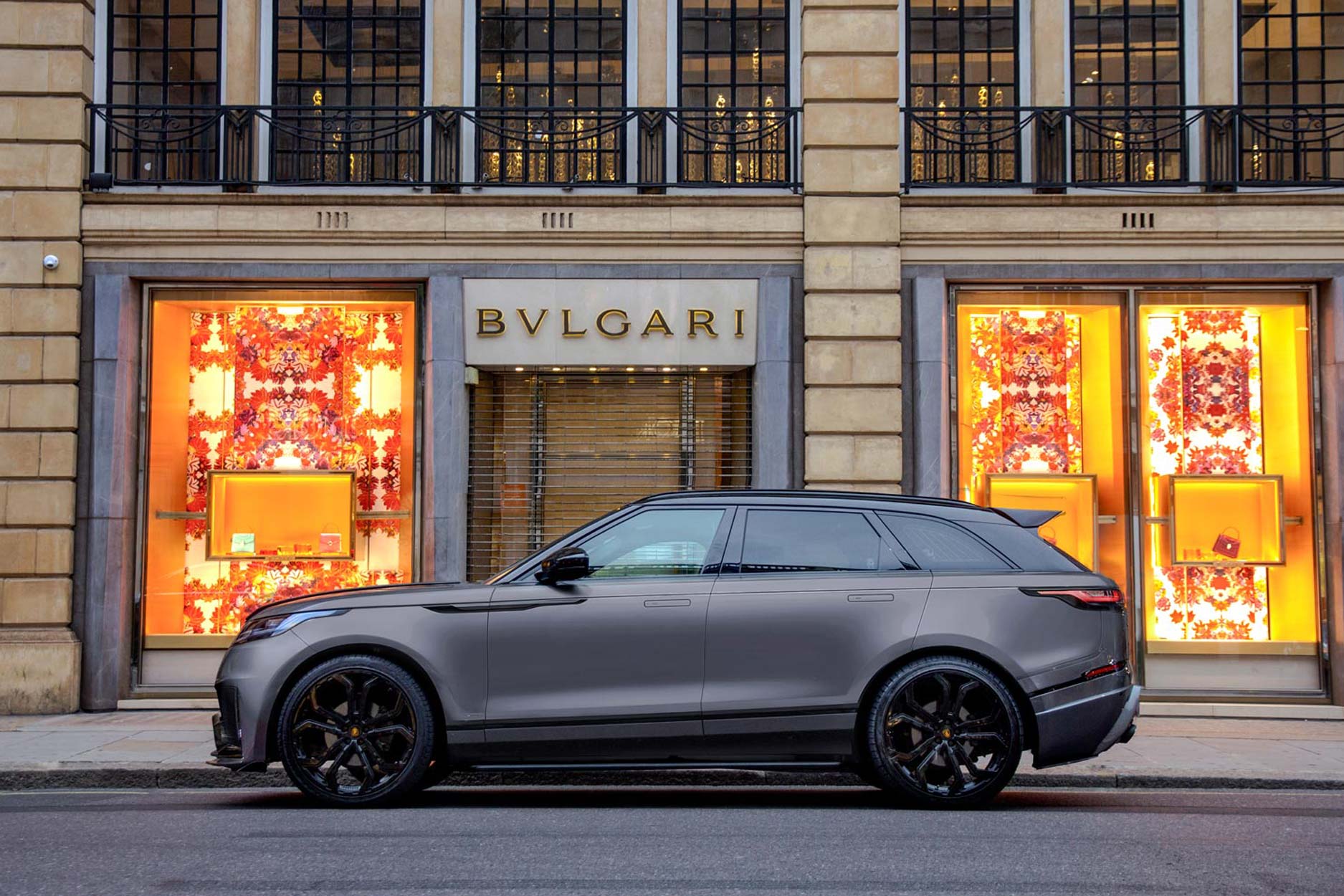 Side view of a Barugzai Range Rover Velar 2017+ . Shot outside a city high street. Fitted with Barugzai Opium 22” alloy wheels, in Gloss Black